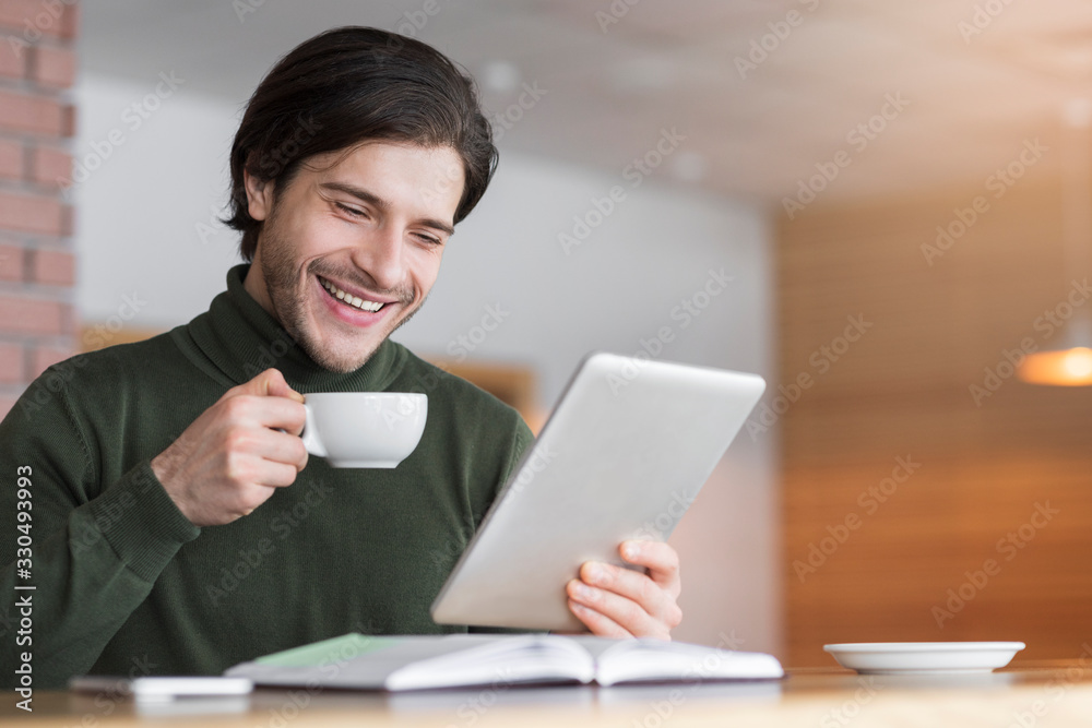 Happy young man reading emails while drinking coffe at cafe Happy young man reading emails while drinking coffe at cafe