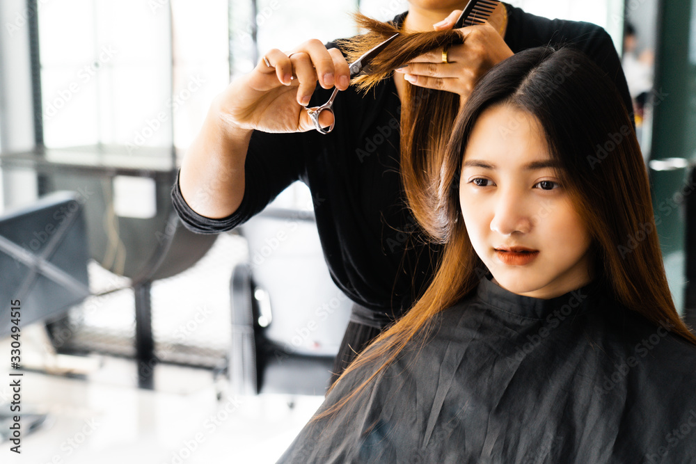 Young Asian beautiful woman having her hair cut at the hairdresser's..Scissors cut the girls hair.Barber student cutting hair using puppet