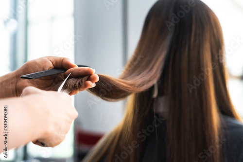 Young Asian beautiful woman having her hair cut at the hairdresser's..Scissors cut the girls hair.Barber student cutting hair using puppet