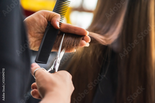 Young Asian beautiful woman having her hair cut at the hairdresser's..Scissors cut the girls hair.Barber student cutting hair using puppet