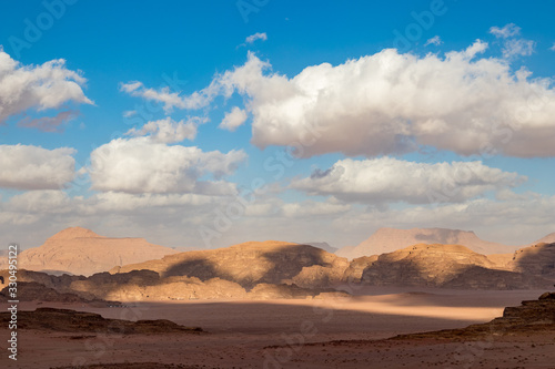 Kingdom of Jordan, Wadi Rum desert, sunny winter day scenery landscape with white puffy clouds and warm colors. Lovely travel photography. Beautiful desert could be explored on safari. Colorful image