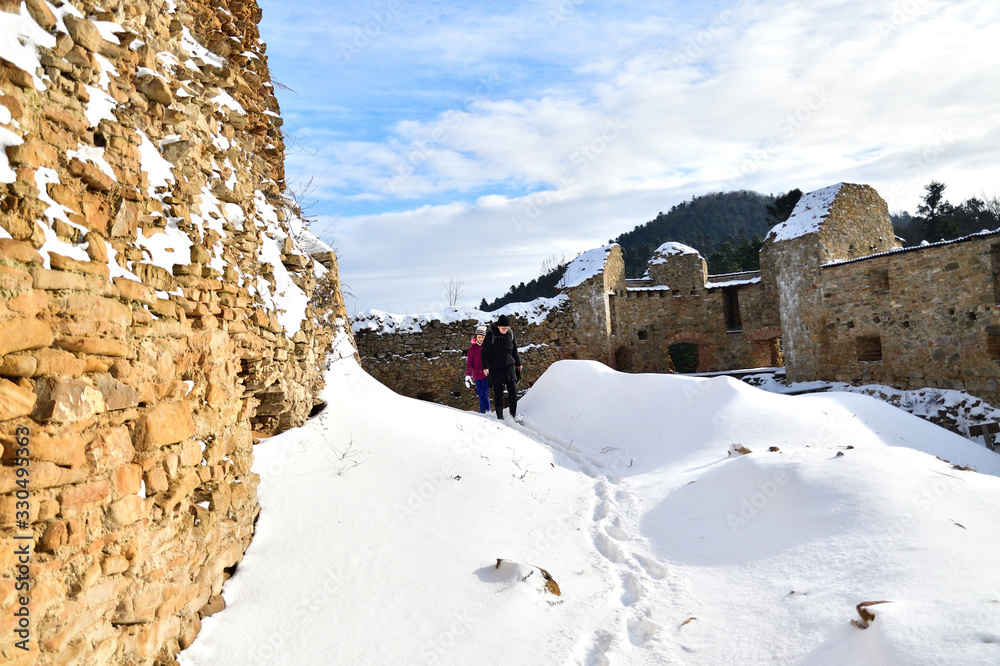 Family trip on castle ruins on the snow in winter Zborov Slovakia 