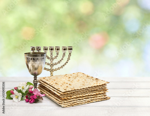 Matzo, wine, menorah and pink flowers apple tree for passover celebration on white background with space for text