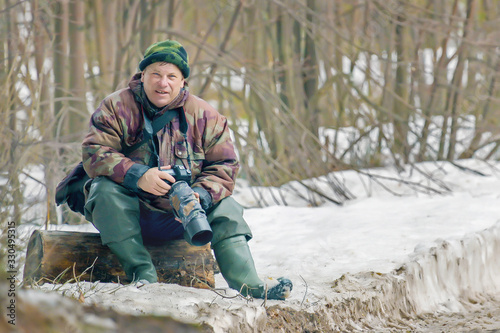 man nature photographer at a halt in the winter forest