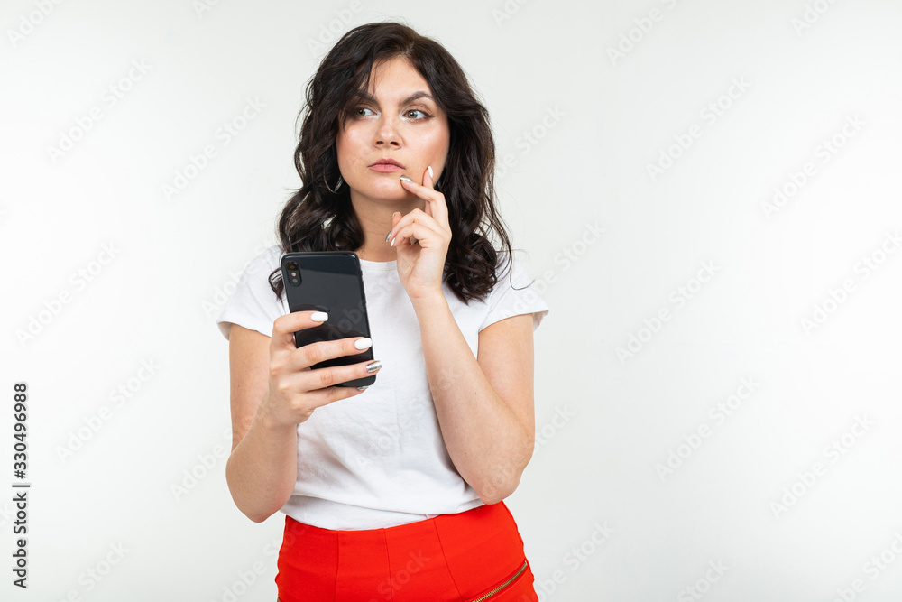 brunette girl is surfing the internet holding a phone in her hands on a white isolated background brunette girl is surfing the internet holding a phone in her hands on a white isolated background