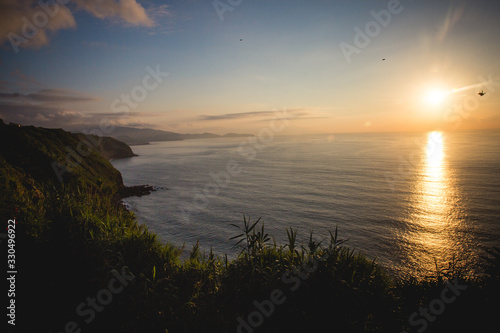 Anochecer en playa de la isla de Sao Miguel en islas Azores de Portugal con reflejo del sol en el agua del mar