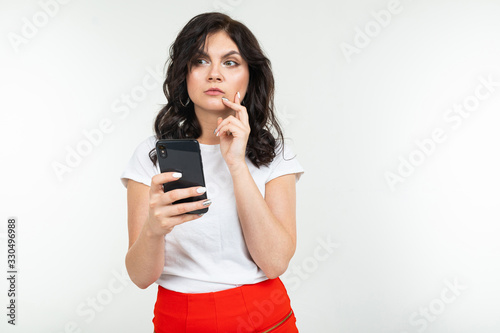 brunette girl is surfing the internet holding a phone in her hands on a white isolated background