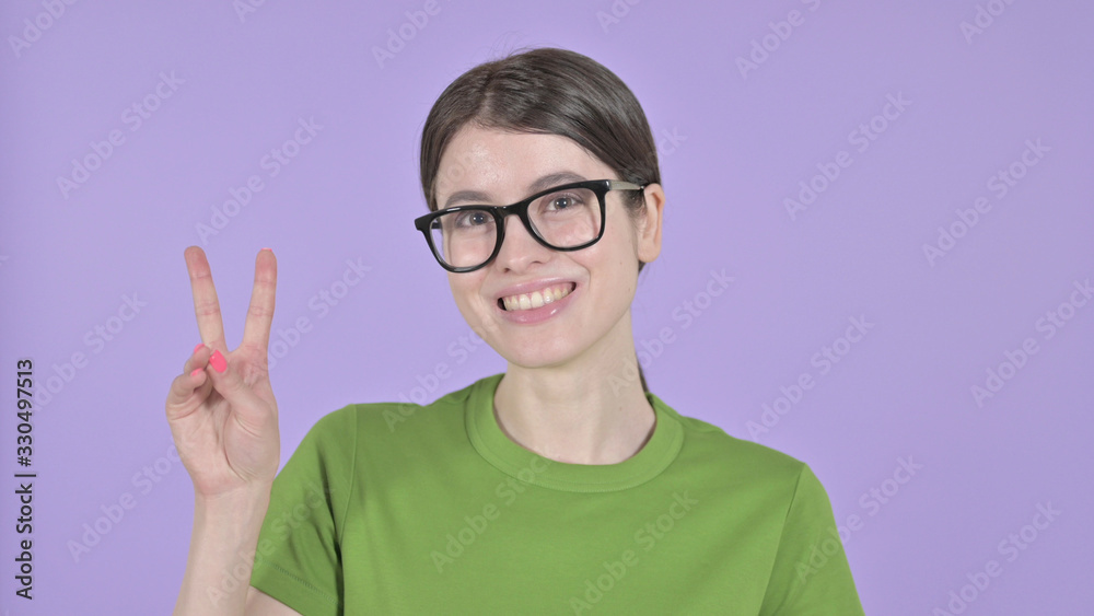 The Young Woman showing Victory Sign on Purple Background