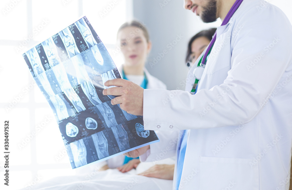 Medical team discussing diagnosis of x-ray image in office Medical team discussing diagnosis of x-ray image in office