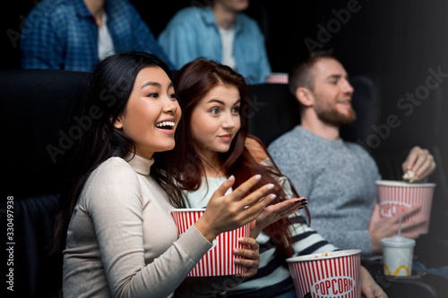 Weekend getaway. Smiling girls enjoying their movie night in cinema