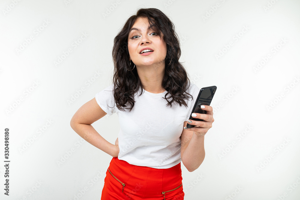 successful brunette young woman with a smartphone in her hands on a white background with copy space successful brunette young woman with a smartphone in her hands on a white background with copy space