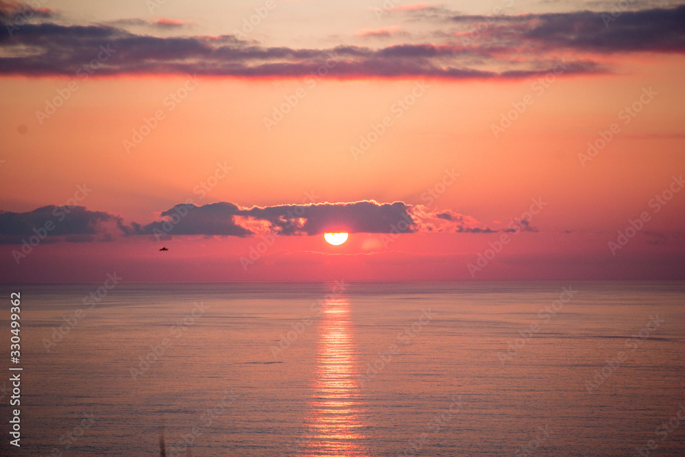 Atardecer en la Isla de Sao Miguel en las Islas Azores de Portugal con los rayos del sol reflejados en el agua del mar con sol rojo intenso