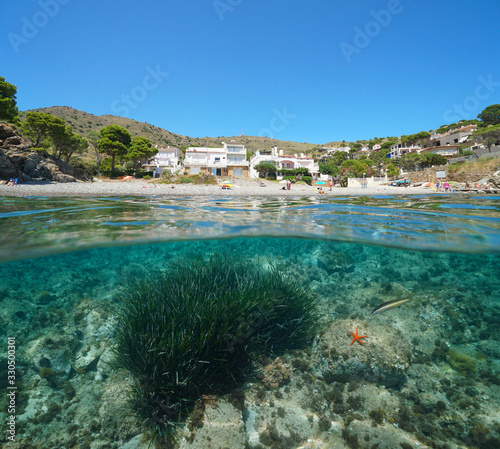 Spain Mediterranean sea summer vacations, beach coastline with buildings, split view over and under water surface, Costa Brava, Colera, Catalonia