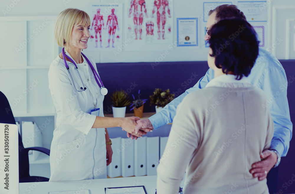 Fototapeta premium Female doctor handshaking a patient's hand and smiling