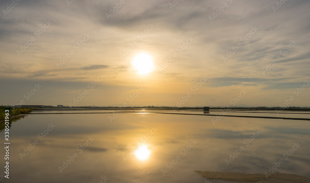 Naklejka premium Salt farm in the morning with sunrise sky and clouds. Landscape of sea salt field in Thailand.