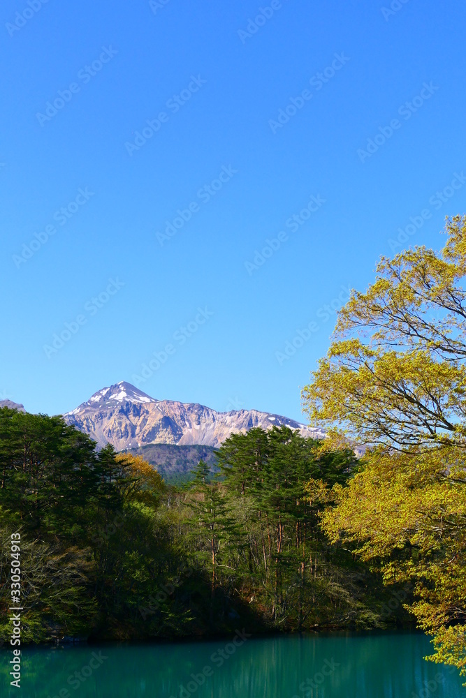 Obraz premium 磐梯朝日国立公園、五色沼湖沼群。新緑の毘沙門沼より磐梯山を望む。北塩原、福島、日本。5月中旬。