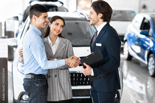 Car Dealer Shaking Hands With Buyers After Successful Deal