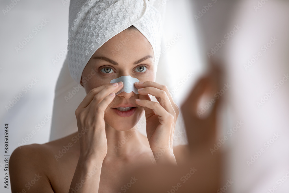 Focused young beautiful woman with towel on head applying cleaning