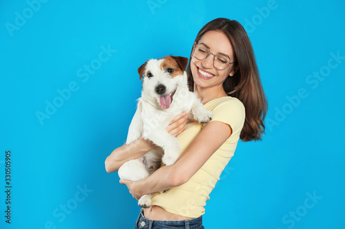 Young woman with her cute Jack Russell Terrier on light blue background. Lovely pet