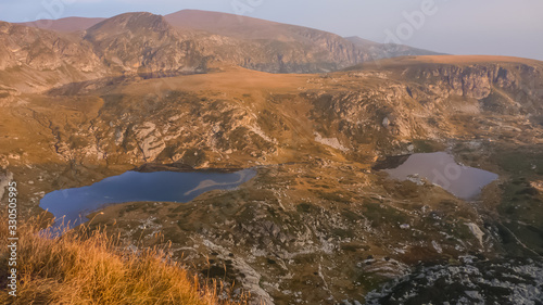 The Seven Rila lakes area, Rila national park,Bulgaria - October CIRCA,2019. Sunset view from the top of Haramiyata mount in late autumn. Seven Rila lakes from above in warm light.