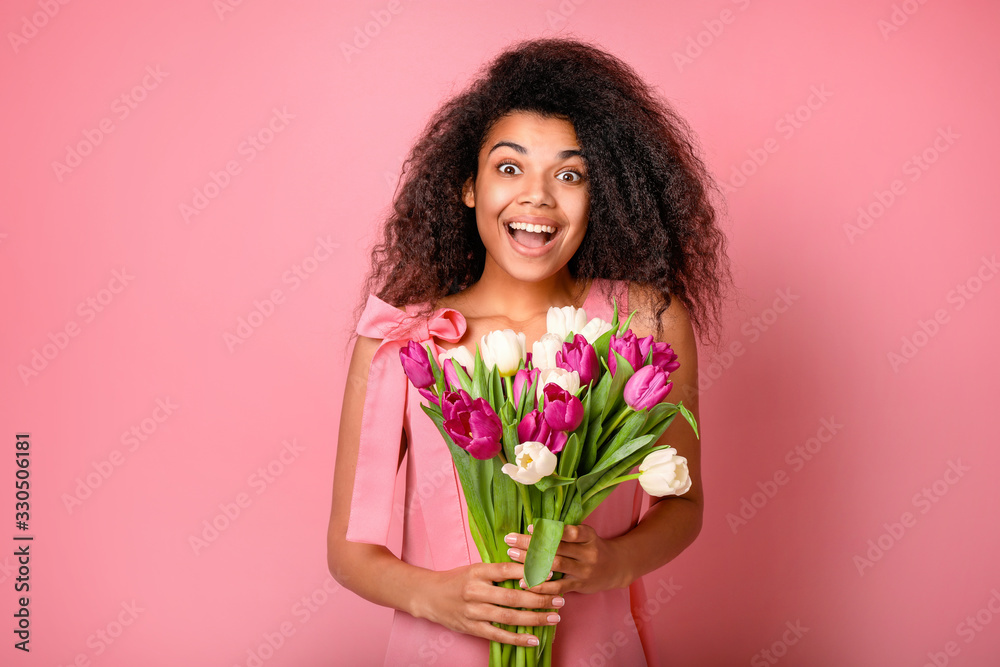 Young african woman with flowers on pink background. Women's day concept Young african woman with flowers on pink background. Women's day concept
