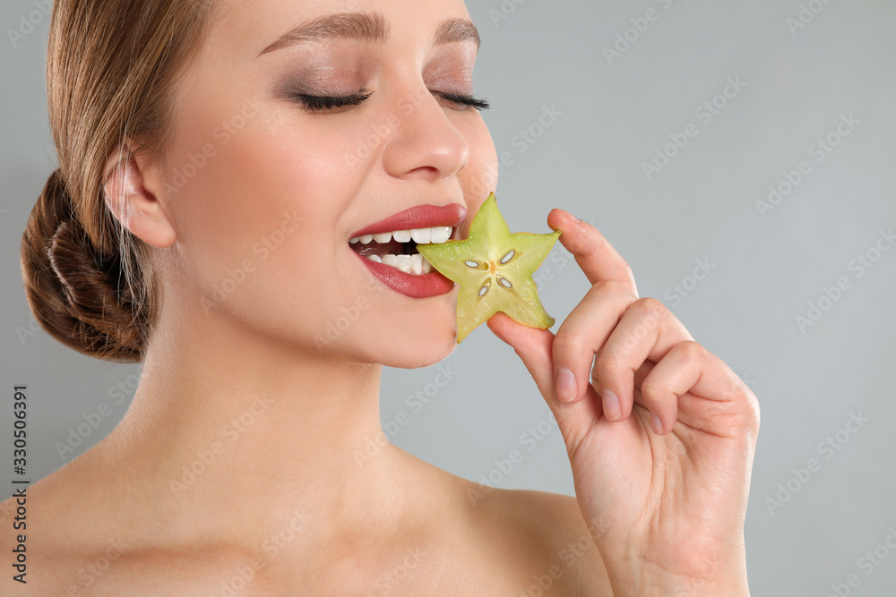 Young woman with slice of carambola on grey background. Vitamin rich food Young woman with slice of carambola on grey background. Vitamin rich food