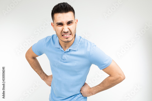 brunette man in a blue t-shirt is angry on a white isolated background © Ivan Traimak