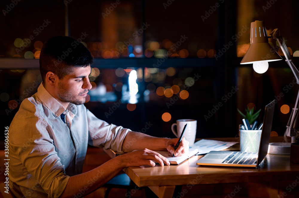 Business Guy Taking Notes Working Overnight Sitting In Office, Low-Light