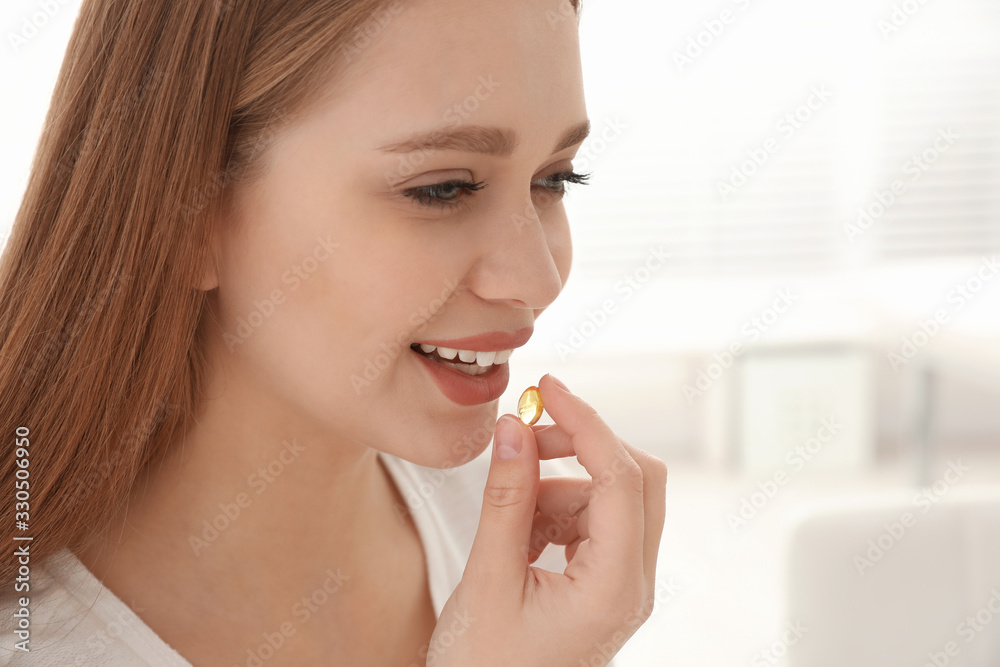 Young woman taking vitamin capsule on light background Young woman taking vitamin capsule on light background