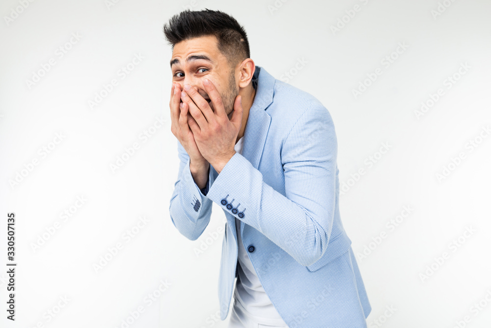 handsome man in classic style laughs covering his face with his hand on a white studio background handsome man in classic style laughs covering his face with his hand on a white studio background