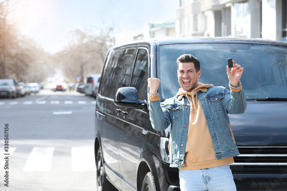 Excited man with key near car on city street. Buying new auto Excited man with key near car on city street. Buying new auto