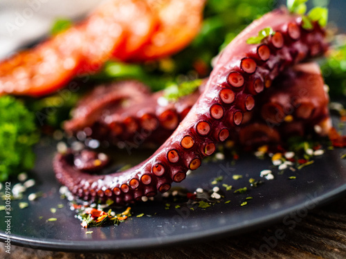 Fried octopus and vegetables on wooden table photo