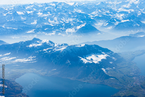 Blue planet earth unique alpine aerial panorama. High altitude aerial view of snow capped central European Swiiss Alps lakes, seen from an airplane cabin window. Enviromental conservation concept.