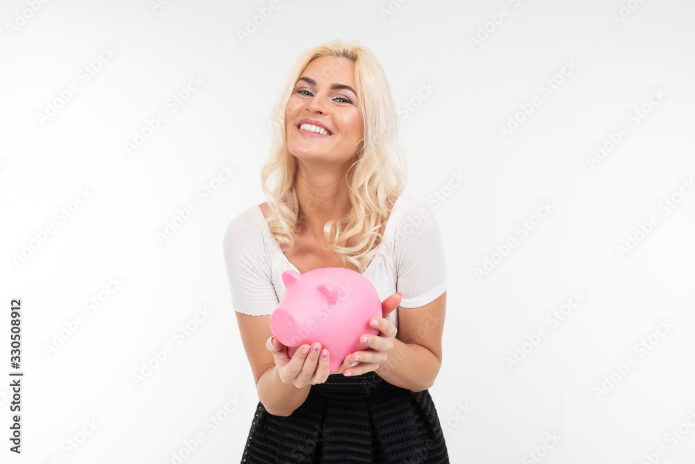 smiling beautiful girl in black and white clothes with a piggy bank in hands on a white background with copy space smiling beautiful girl in black and white clothes with a piggy bank in hands on a white background with copy space