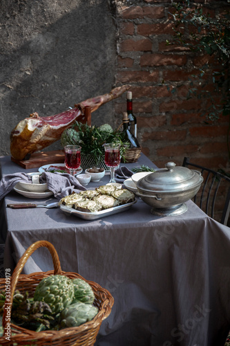 Mediterranian Tablecloth with whole ham jamon serrano leg, baked artichokes and red wine photo