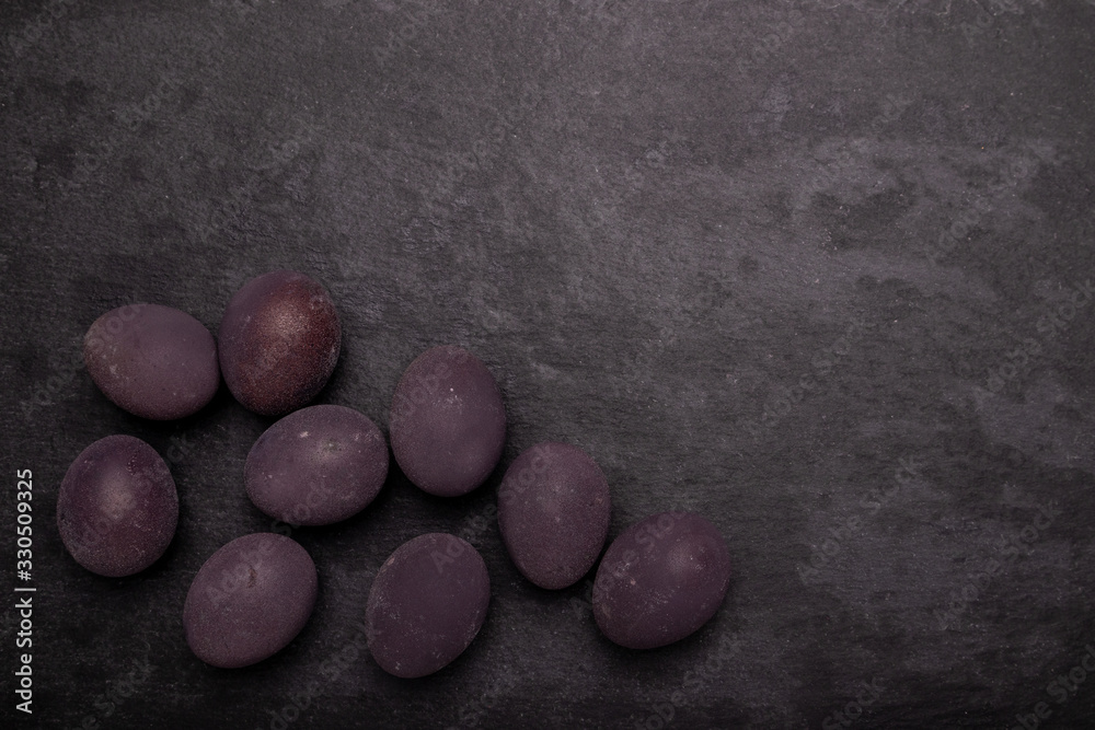 Dark easter eggs on stone table with black backdrop. Colored with wine. Dark easter eggs on stone table with black backdrop. Colored with wine.