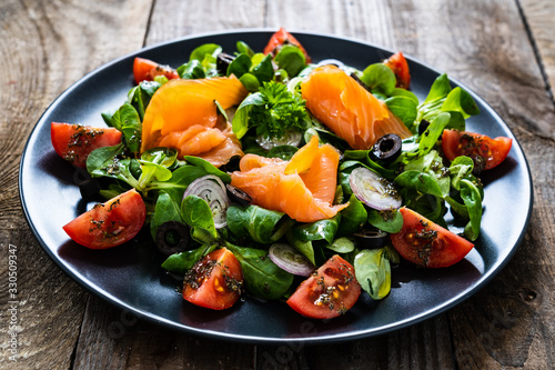 Salmon salad - smoked salmon and vegetables on wooden background