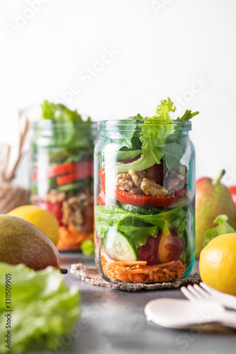 Healthy homemade mason jar salad with fresh pear tomatoes, carrots and herbs. Vegetarian concept.