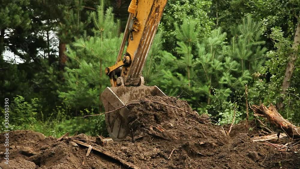 Excavation work at a construction site. Excavator bucket lifts the ground. Construction machinery, ground works. Close-up of excavator working on construction site.