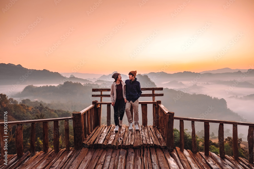 Fototapeta premium Happy couple Enjoying Freedom on top of The morning mist Thailand mountains covered with fog sunrise time Mae Hong Son, Thailand