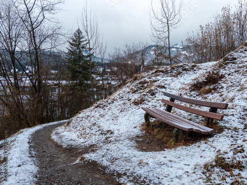 A lonely bench slightly covered with the snow on a cloudy day. photo