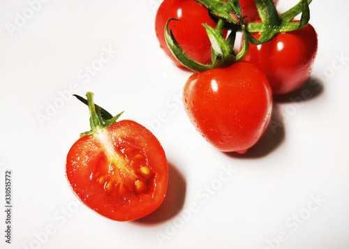 Vegetable series - Small vine cherry tomatoes and one small cut isolated on white background © Kinsei