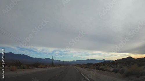 4K. POV view of car driving on highway in the California states. A car drives on a freeway. Asphalt with yellow line at new road. Mojave desert.