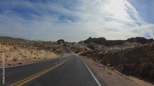 4K. POV view of car driving on road of highway at day in USA. Drive on an empty road in the dark evening. Asphalt with yellow line at new road in Valley of Fire. Nevada state.
