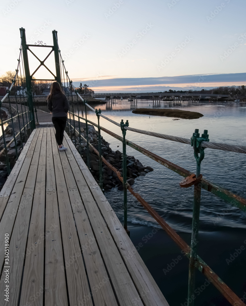 Sunrise on Wiggly Bridge in York Harbor with solo female - York, Maine. Sunrise on Wiggly Bridge in York Harbor with solo female - York, Maine.