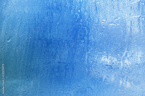 The surface of a foggy window glass with raindrops. Background. Bad weather, rain.