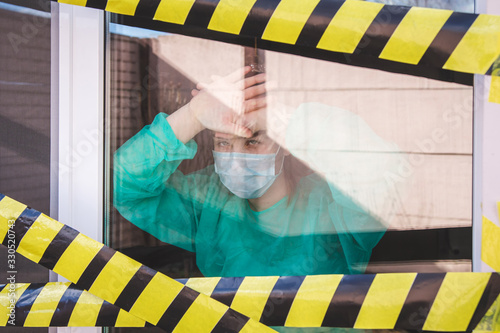 coronavirus covid 19 quarantine warning tape  window of the quarantine room in the hospital with coronavirus cvid19, concept of quarantine of the coronavirus pandemic. Girl in a mask behind a glass photo