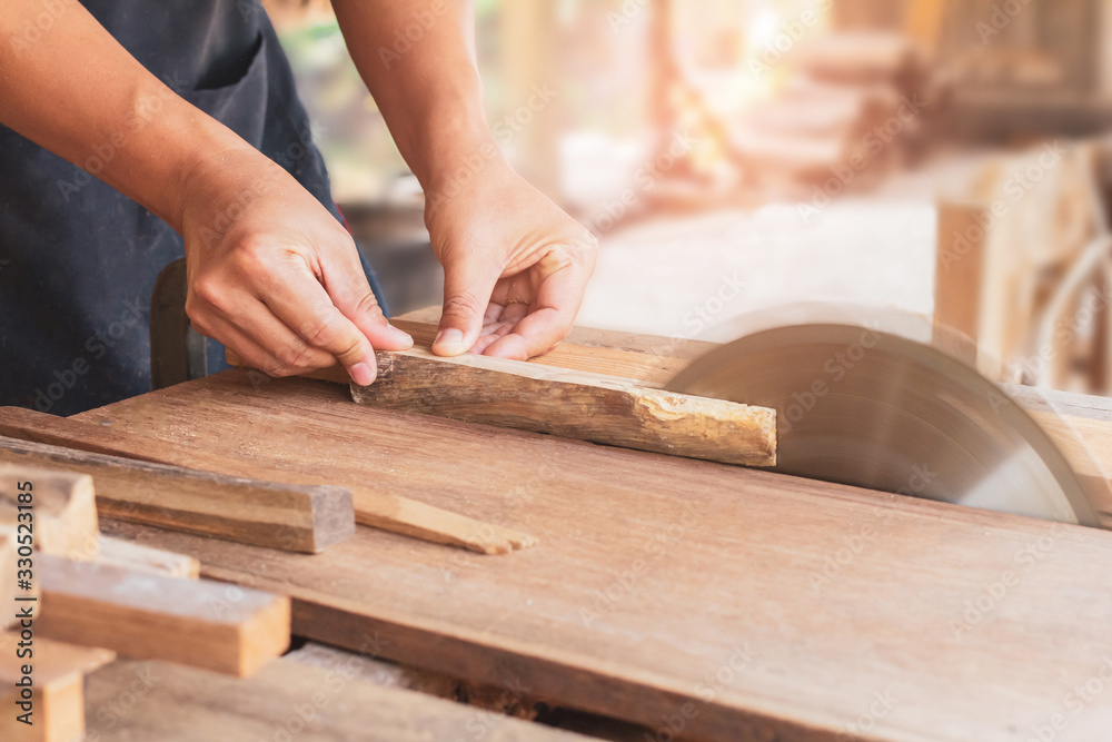carpenter using a circular saw cutting a plank of wood working in workshop at home carpenter using a circular saw cutting a plank of wood working in workshop at home