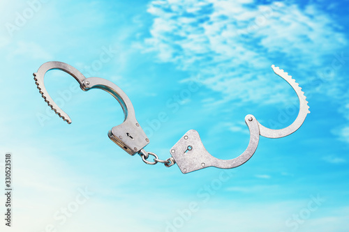 Open handcuffs on a sky background as a symbol of freedom photo