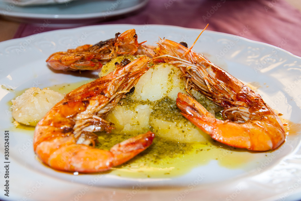 Shrimps in garlic sauce with boiled potatoes on a plate Shrimps in garlic sauce with boiled potatoes on a plate